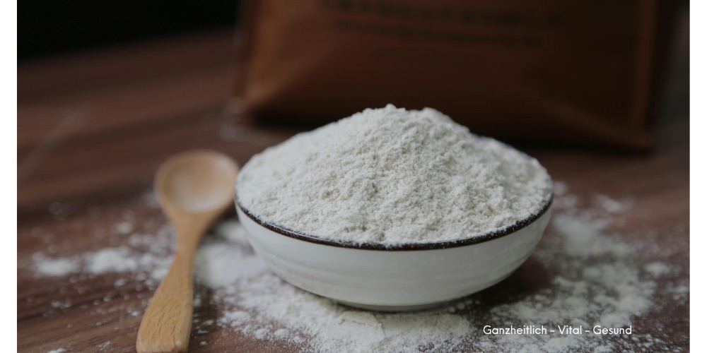 Feines helles Mineralpulver in einer Schale mit Holzlöffel